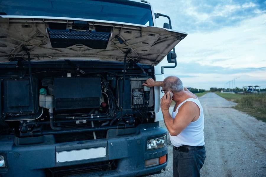 Man calling a truck mechanic to fix a broken down transport truck